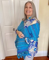A woman in a blue shawl standing in a room, looking elegant and composed.