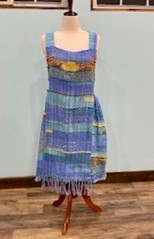 Woven dress with stipes in shades of blue on a Mannequin.