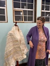 Women standing next to a wowen shawl.