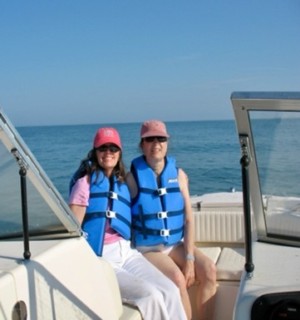 Two women in blue life jackets on a boat.